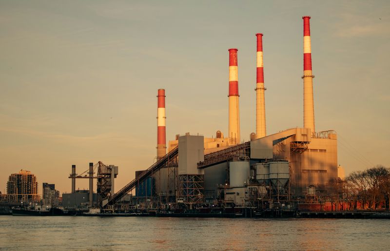 Ravenswood Generating Station power plant with red and white striped smokestacks along the waterfront in Queens, New York at sunset
