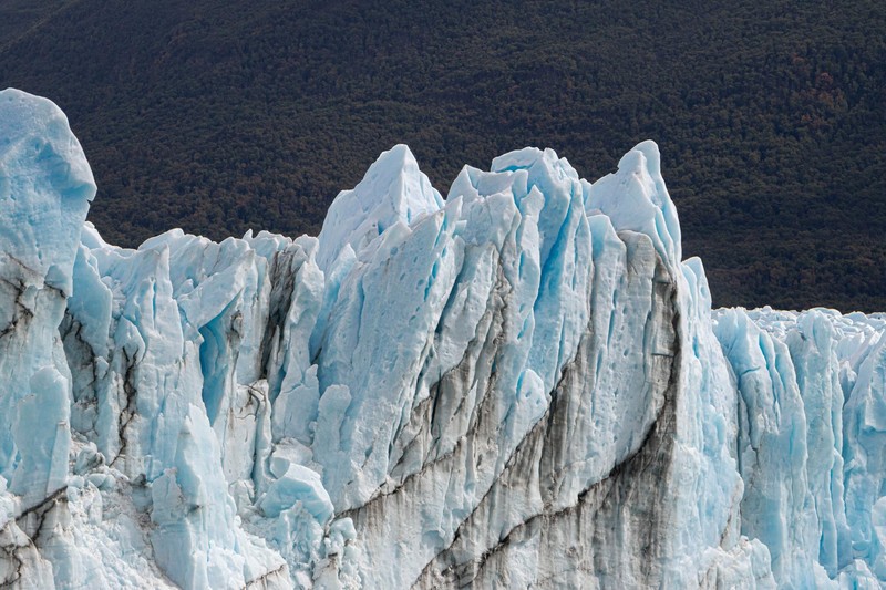 Blue glacier ice formations against a mountainous backdrop on a cold winter day