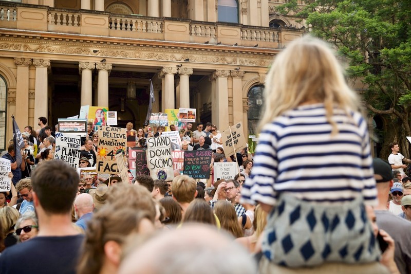 A young girl attends a climate rally in Sydney, looking toward the crowd of protesters